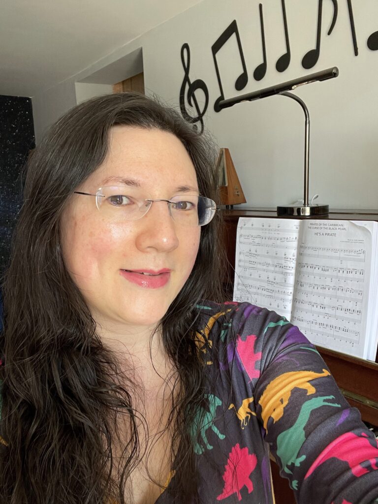 Introducing Myself to The Littlest Students - a 4 Year Old! 2 Jen wearing her dinosaur Popsy Dress, about to play her piano in her studio. Introducing myself to the youngest students!