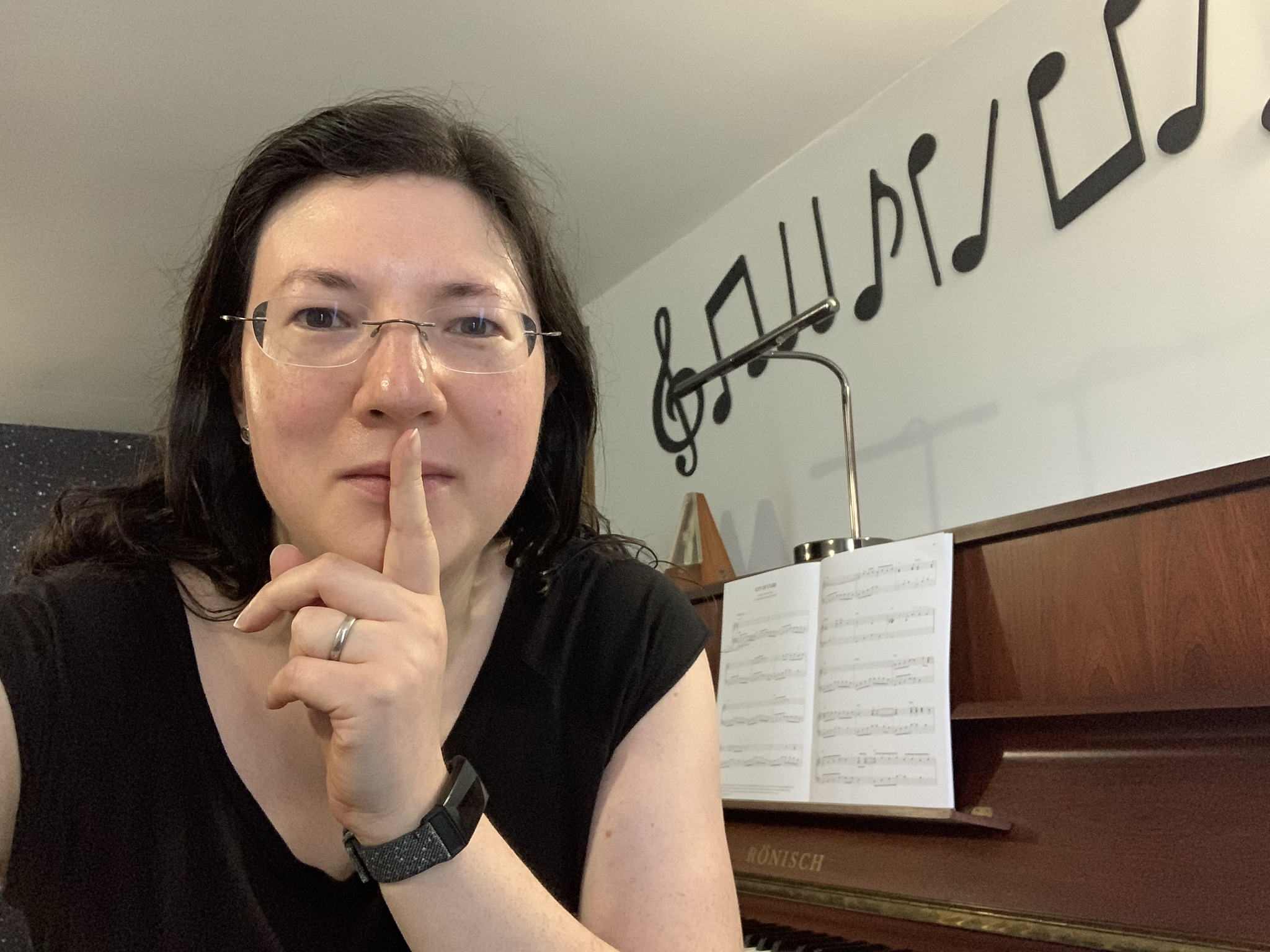 Jen with her finger on her lips by her piano.