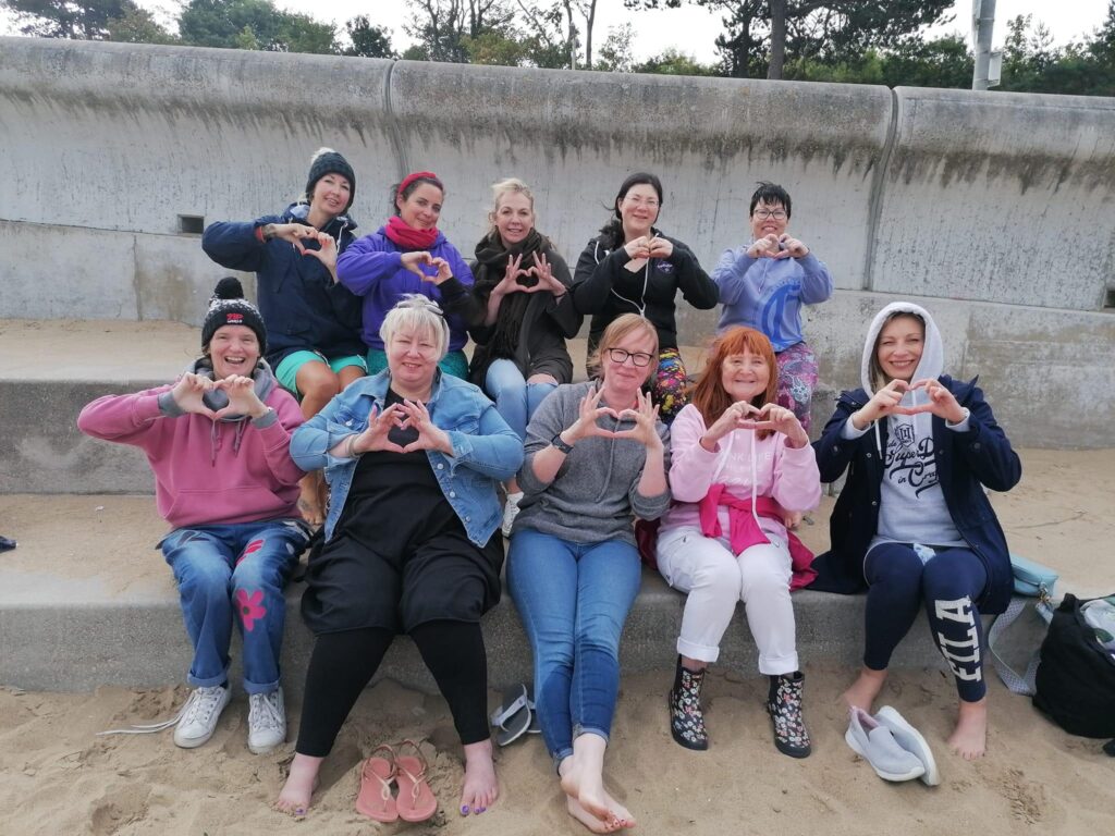 New Term, New Chapter. 3 A group picutre on colwyn bay beach, everyone is doing the heart sign with their hands and looking happy!