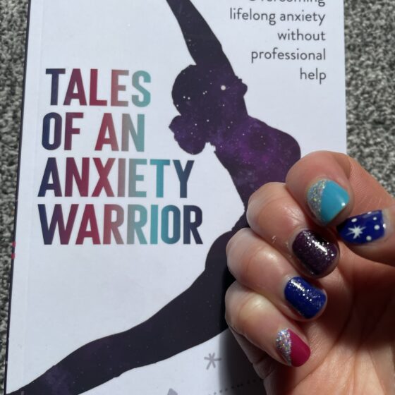 A copy of my new book " Tales of an Anxiety Warrior ", with my matching nails against the cover