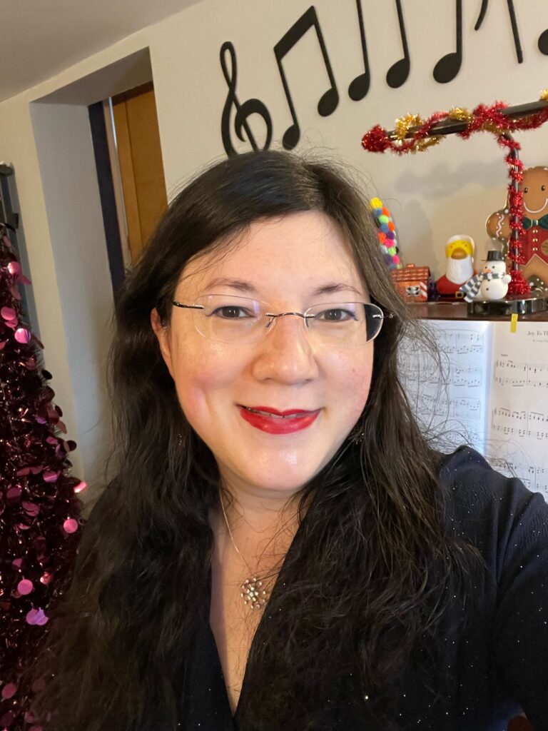 A selfie of me smiling with christmassy backdrop and my piano. 