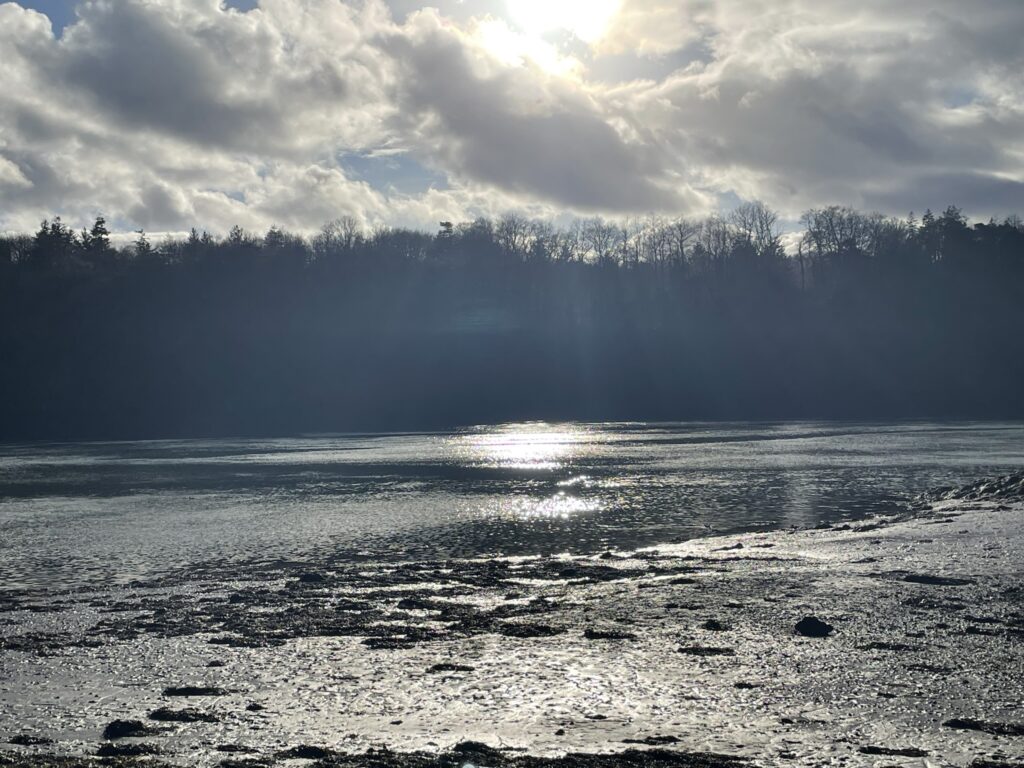 A hazier view across the menai straits where the sun is just hitting the water at a certain angle.