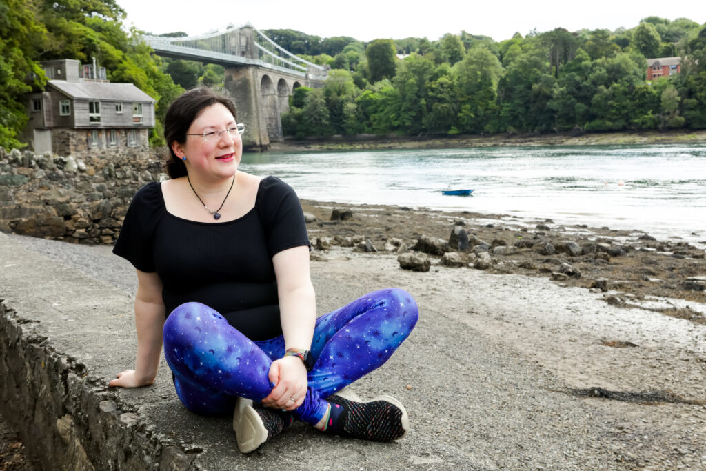 I had a Brand Photoshoot and it was so much fun! 32 a photo of me sat on the wall with the menai bridge behind me.