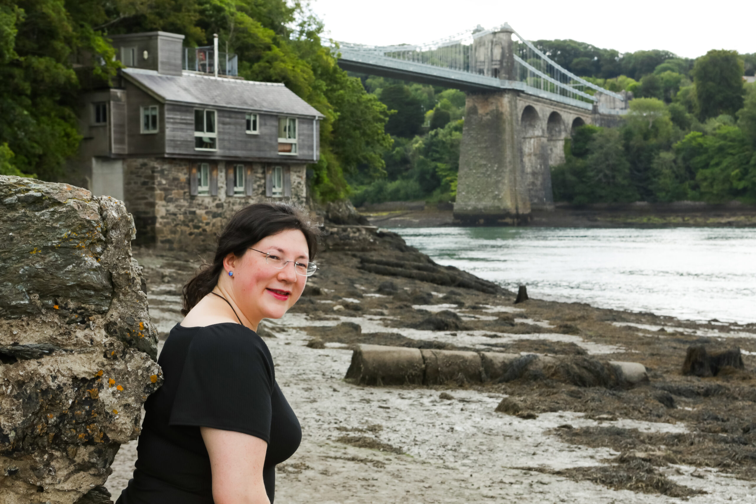 SOCIAL LINKS 1 Jen is looking behind her whilst on a walk on the belgian promenade in Menai Bridge. Menai Bridge itself is in the background.
