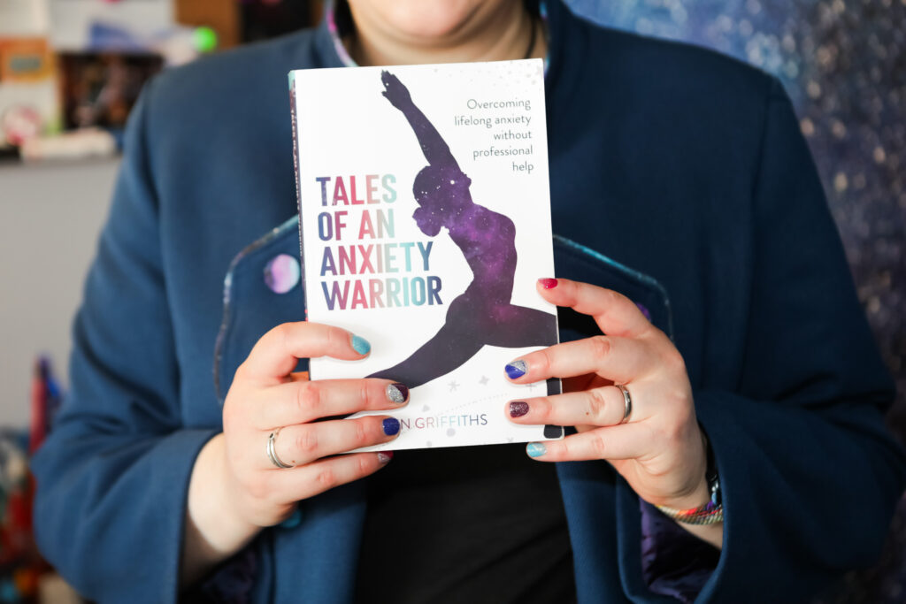 I had a Brand Photoshoot and it was so much fun! 49 Jen holding her book "Tales of an Anxiety Warrior", wearing her tailor made jacket.