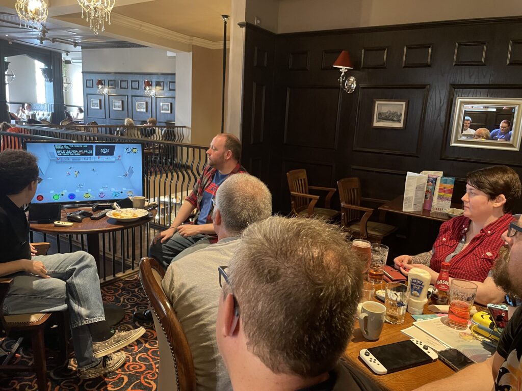 An alternative angle of a selection of people playing Nintendo Switch on a TV