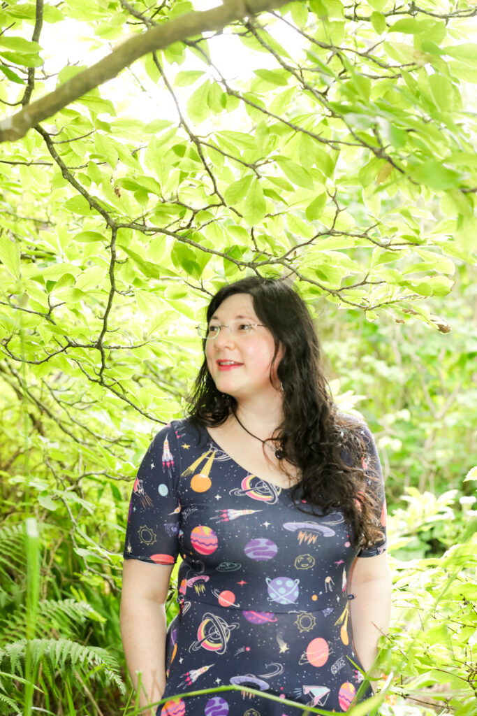 Stress & Anxiety- How to be Positively Calm 2 Jen is in her space themed dress, gazing into the distance under a very leafy green tree. Calm no stress.