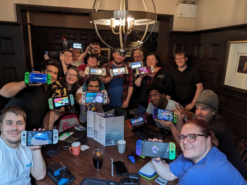 A whole group photo of 15 of us. 14 of us are holding our switch consoles to the camera with a screenshot featured. 