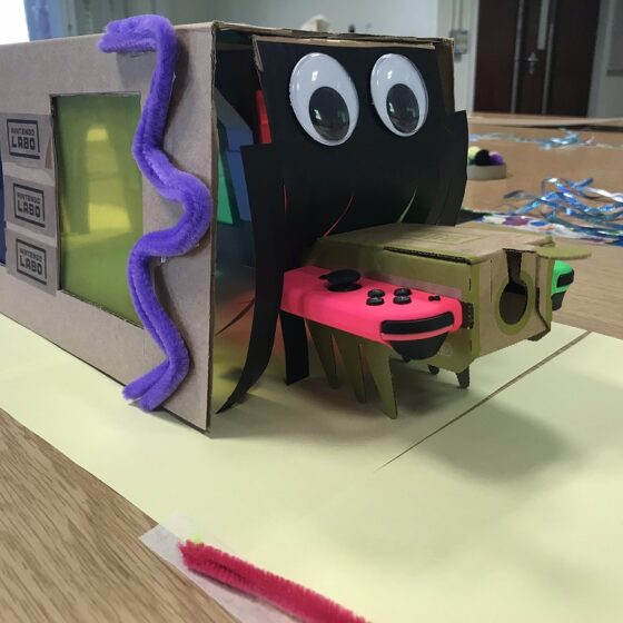 paper crafted "Munch monster" for Nintendo Labo bug on an obstacle course. big googly eyes, and a "curtain" which the bug goes through to the other side.