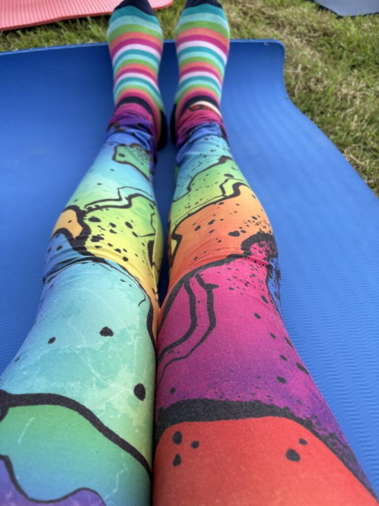 Speaker at a Brand New Yoga Festival- June 2024 - a Major 2024 Goal accomplished! 14 a photo of my rainbow leggings, and rainbow socks on my yoga mat.