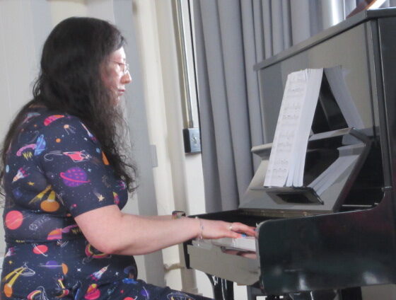 Me in my space dress playing for my first summer concert on a black upright piano