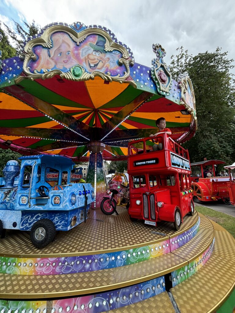 Making the most of the Summer Holidays 2024! 2 A carousel merry go round, with a red double decker bus featured.