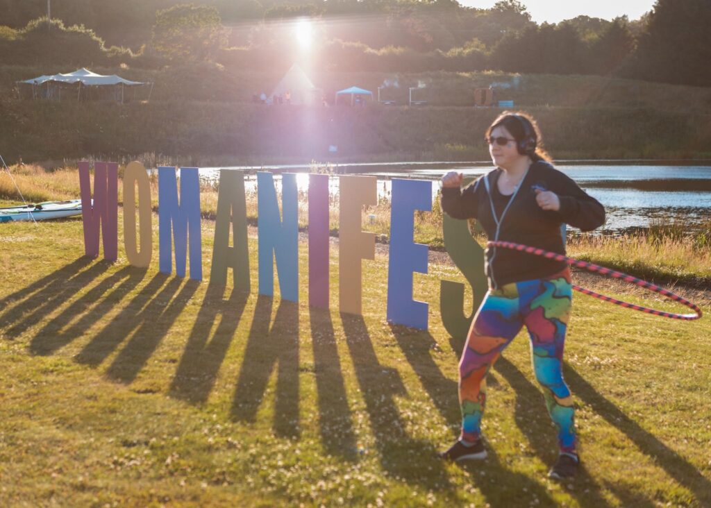 Summer has Started here, Exciting plans ahead! 16 me hula hooping at sunset next to the big "WOMANIFEST" letters by the lake.