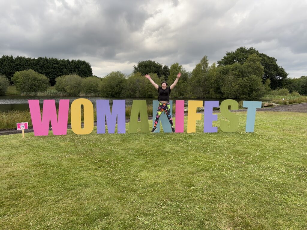 Festivals of 2025 Fulfilled & 3 Public Speaking Goals Smashed! 9 picture of me doing the jumping star pose against the Womanifest letters.
