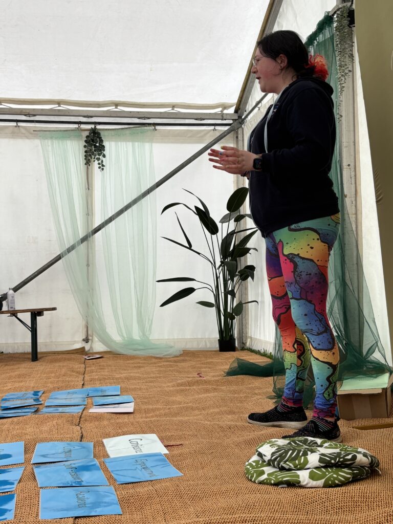 Festivals of 2025 Fulfilled & 3 Public Speaking Goals Smashed! 14 side profile picture of me gesturing at the audience. Rainbow leggings, branded hoodie.