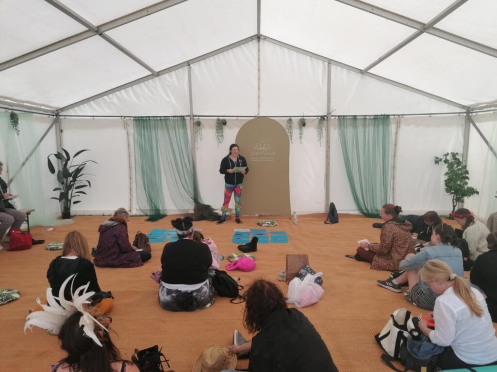Festivals of 2025 Fulfilled & 3 Public Speaking Goals Smashed! 13 picture of me talking to the audience, holding one of my flash cards. Rainbow leggings, branded hoodie.