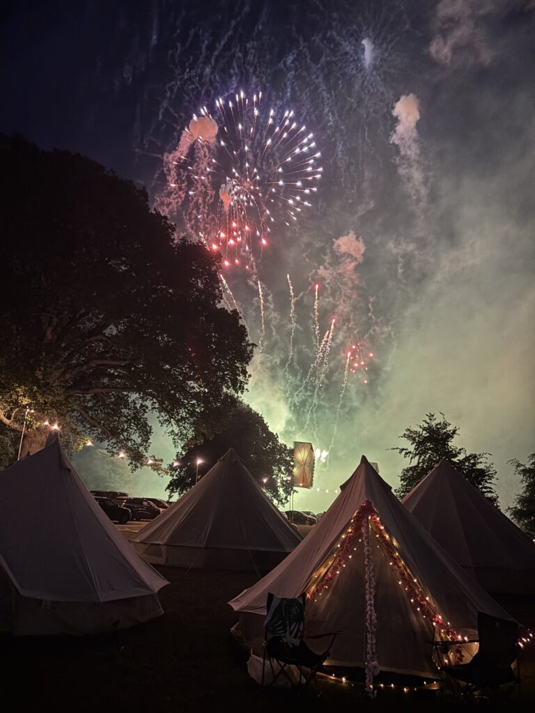 Summer 2026 is a Great Balance! 18 A picture over bell tents at the night sky with a colourful display of fireworks overhead.